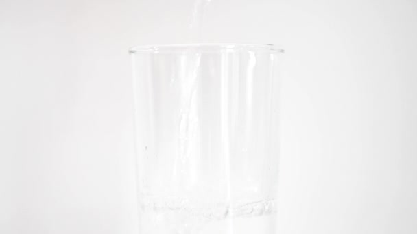 背の高いガラスに新鮮な水が注ぎ込まれ 白い背景に ブライアン ホーム ニールセンの株式映像 — ストック動画