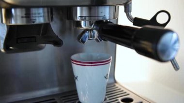 Büyük bir espresso makinesinden küçük, kırmızı, beyaz ve siyah bir fincana eklenen sıcak espresso videosu. Brian Holm Nielsen 'in stok video görüntüleri
