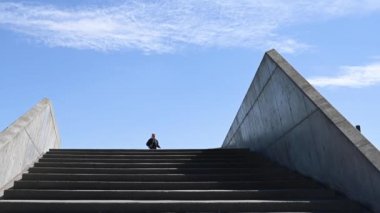 Çekici genç İskandinav, Kafkasyalı kadın, egzersiz yapmak için merdivenlerden iniyor, ağır çekimde. Kamera ona yukarıdan bakıyor. Mavi gökyüzü ve bulutlarla güneşli güzel bir gün. Brian Holm Nielsen 'in stok video görüntüleri
