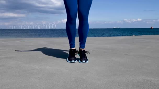 魅力的 フィット 若い北欧 白人女性 運動としてロープをジャンプ 彼女の足だけがフレームには カメラに直面している 彼女は海上の桟橋で運動している 青空といくつかの雲の美しい晴れた日 — ストック動画