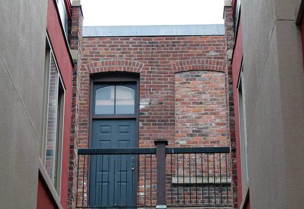Κλειστή μαύρη πόρτα δίπλα Bricked πάνω από το παράθυρο σε ένα σοκάκι — Φωτογραφία Αρχείου