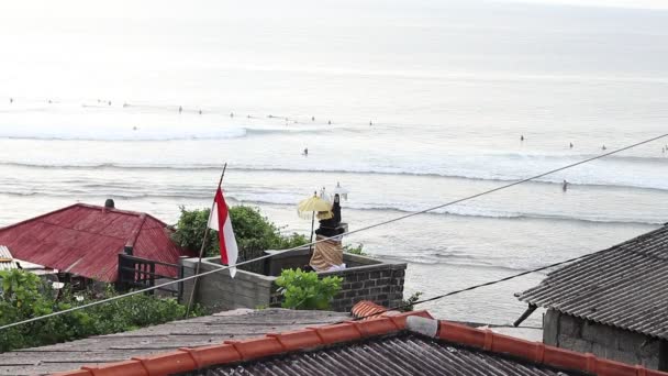 Jóvenes surfistas montan las olas en el océano Índico durante el atardecer, exótico Bali, Indonesia. Vista desde lejos. Full HD 1920x1080, 50 fps. Vista desde la montaña . — Vídeo de stock