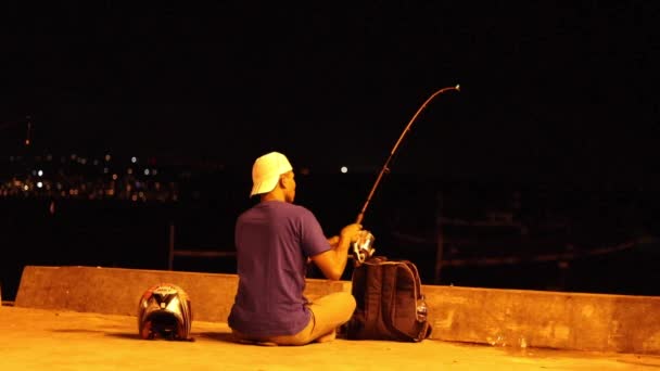 Indonesian fisherman at night, waiting when the bite. Jimbaran, Bali, Indonesia, a fishing village. Yellow lighting. — Stock Video