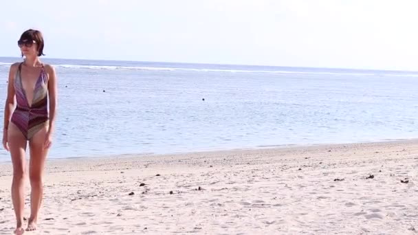 Sexy attractive young caucasian woman on a beautiful tropical beach, walking on the beach of Bali island, Indonesia. Tattoo on her back. Enjoying nature and lifestyle on vacation. Ocean on background. — Stock Video