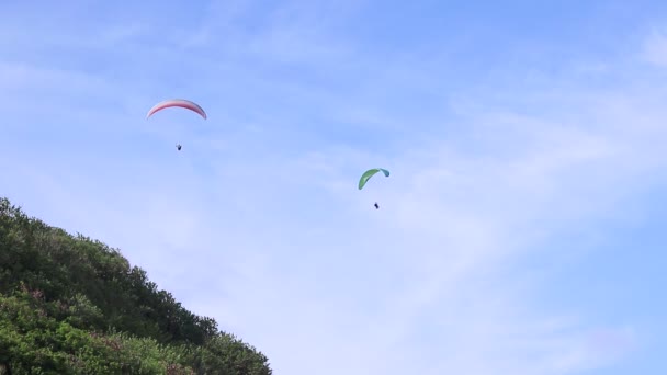 Paraglidové létají přes úžasnou horu u pláže, na ostrově Bali, v Indonésii. Krásný výhled, nebe a hora plné rostlin. Full HD, 50 fps, 1080p. — Stock video