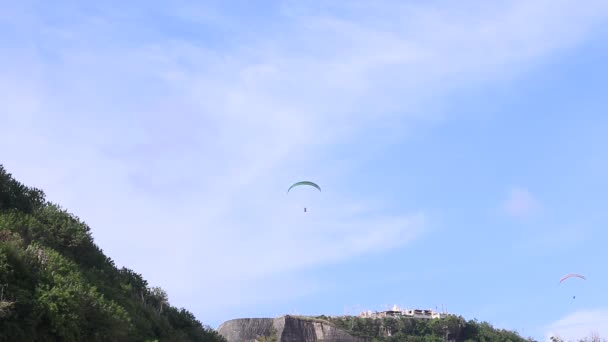 Paraglidové létají přes úžasnou horu u pláže, na ostrově Bali, v Indonésii. Krásný výhled, nebe a hora plné rostlin. Full HD, 50 fps, 1080p. — Stock video