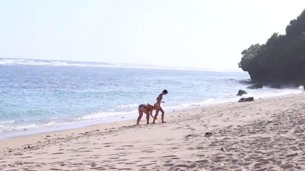 Fiatal nők megtalálja a tengerparton kagylók. Óceán. Bali, Indonézia. — Stock videók