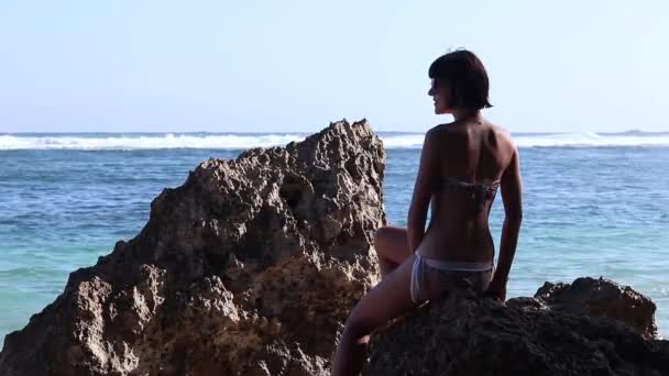 Silueta de una hermosa mujer Yoga por la mañana en una roca de playa junto al océano. Jovencita sexy en traje de baño. Tatoo en su espalda . — Vídeos de Stock