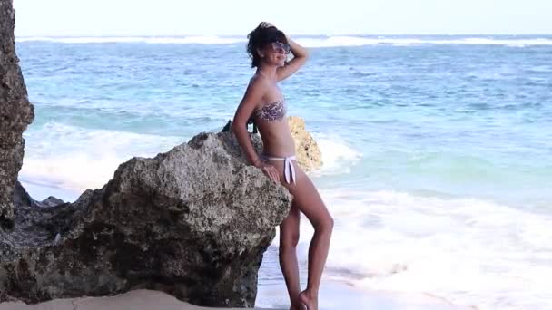 Sexy menina de verão - Jovem mulher em um swimwear ficar na praia perto do oceano e rochas . — Vídeo de Stock