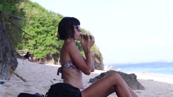 Sexig ung kvinna blåser blåsa en grön ballong, ung kvinna på stranden. Ocean, Bali, Indonesien. — Stockvideo
