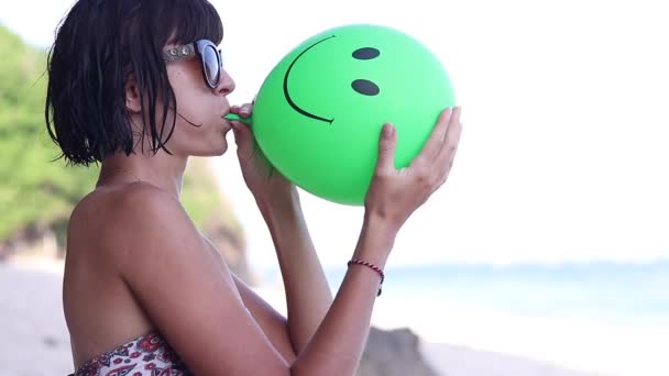 Sexy joven mujer soplando inflando un globo verde, joven hembra en la playa, cámara lenta. Océano, Bali, Indonesia . — Vídeo de stock