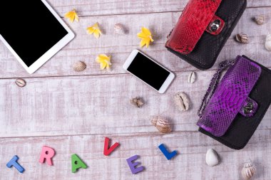 Şık olmak. Moda Ladys aksesuarları. Lüks python deri çanta, kozmetik, tablet, smartphone, plumeria çiçekler, kabukları. Moda seti, üstten görünüm, ahşap arka plan detay. Kelime 