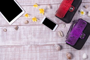 Bir moda blogger bir temel nesneleri yükü. «Ana sayfa» moda piton yılan derisi çanta, akıllı telefon, tablet pc, görünümünü kabukları. Plumeria frangipani çiçekler. Ahşap arka plan.