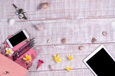 Bir moda blogger bir temel nesneleri yükü. «Ana sayfa» moda piton yılan derisi çanta, akıllı telefon, tablet pc, görünümünü kabukları. Plumeria frangipani çiçekler. Ahşap arka plan.