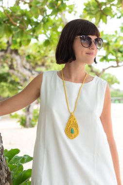 Yakın çekim ile deri aksesuarları, açık hava, plaj tropikal Bali Adası, Endonezya'nın kadın moda. Güneşli bir gün. Gözlüklü genç kadın. Moda görünümü. Ağaçlar ve bitkiler bir arka plan üzerinde.