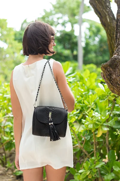 Schöne Sommerfrau mit Sonnenbrille und Luxus handgemachte Schlangenhaut Python schwarze Handtasche. schönen asiatischen Hintergrund. posiert am Strand der tropischen Bali-Insel, Indonesien. — Stockfoto