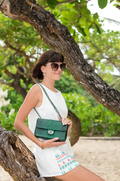 Güzel yaz güneş gözlüğü ve lüks el yapımı yılan derisi python çanta yeşil renkte bir kadınla. Güzel arka plan. Tropikal Bali Adası, Endonezya kumsalda poz.