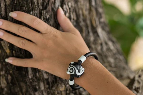 Jovem mão mulher com pulseira de pele artesanal no fundo da árvore . — Fotografia de Stock