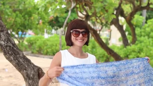 Mujer sexy de cámara lenta caminando y jugando en la playa, girando con bufanda de seda. Hermoso fondo con palmeras y otras plantas asiáticas. Bali, Indonesia . — Vídeo de stock