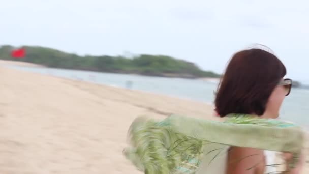 Femme qui court à la plage. Jeune jolie femme avec des lunettes et écharpe en soie verte, Bali, Indonésie . — Video