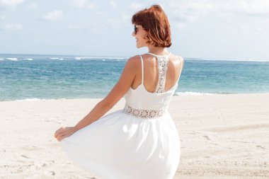 Endonezya Bali tropikal plaj adada arkadan görünüşü beyaz elbiseli genç kadın. Okyanus görmek.