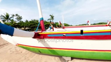 Mavi gökyüzü ile sahilde ahşap renkli balıkçı teknesi. Nusa Dua, Bali, Endonezya. Ağır çekim.