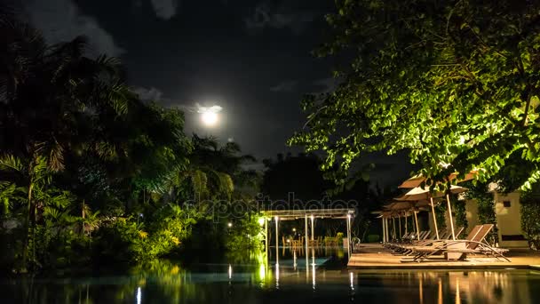 Vollmond im Zeitraffer über der tropischen Insel Bali, Indonesien. Blick vom Schwimmbad. erstaunliche Wolken und grüne Bäume, Licht auf dem Wasser. Dunkle Szene. — Stockvideo
