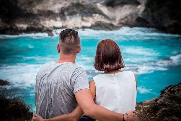 熱帯の魅力的な若い幸せなロマンチックなカップルの島ヌサ ・ レンボンガン島、インドネシア。アジアの彼らの休暇の間に幸せなハネムーン。崖の上のロマンチックなシーン。背景に海. — ストック写真