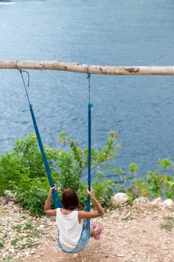 Tatil kavramı. Genç kadın cliff beach salıncakta salıncakta. Seçici odak. Tropik ada Nusa Lembongan, Endonezya. Okyanusun bir arka plan üzerinde.