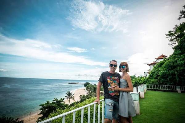 Happy Romantic honeymoon couple posing on the cliff near the beach. Tropical Bali island, Indonesia.