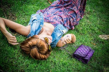 Bir güzel şık beyaz esmer kadın güneş gözlüğü ve lüks yılan derisi python çanta park, Nusa Dua içinde Bali, Endonezya poz ile portresi. Asya. Güneşli bir gün, yeşil arka plan.