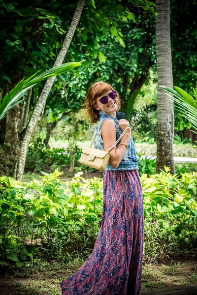 Retrato de una hermosa morena caucásica de moda con gafas de sol y bolso de piel de serpiente de pitón de lujo posando en el parque de Nusa Dua, Bali, Indonesia. Asia. Día soleado, fondo verde . — Foto de Stock