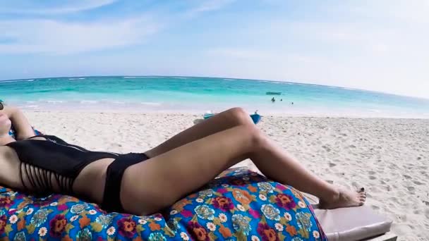 Young bikini woman sunbathing on the beach of tropical Bali island, Indonesia. Slow motion. Asia, sunny day, summer. Lady in sunglasses. — Stock Video