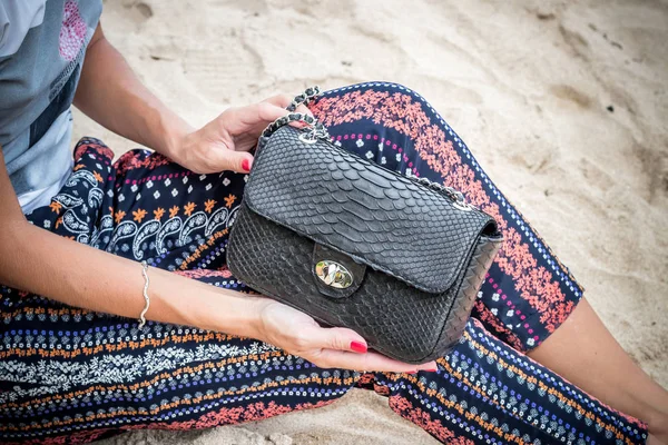 Close up of luxury handmade snakeskin python handbag in woman hands. Tropical Bali island.