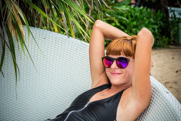 Ontspannen op de ligstoel. Mooie jonge vrouwen in zonnebril ontspannen op de ligstoel op het strand. Sexy vrouw portret. — Stockfoto