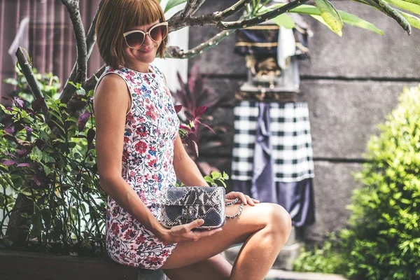 Ritratto estivo di una bella ragazza sexy con occhiali da sole e lussuosa borsa in pitone di pelle di serpente fatta a mano in piscina. Moda outdoor. Isola tropicale di Bali, Indonesia . — Foto Stock