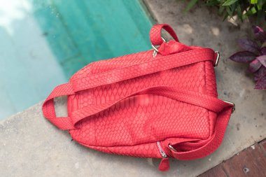 Yüzme Havuz kenarında şık kırmızı deri snkeskin python sırt çantası. Bali Adası.