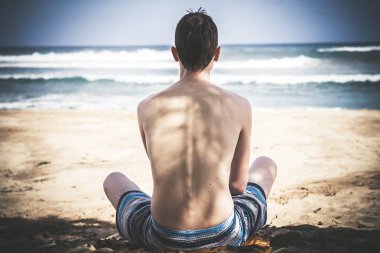 Yakışıklı bir genç adam bir iskelesi ile tropik ada zemin üzerinde yoga yaparken