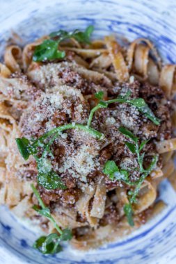 Tabak lezzetli lezzetli Bolognaise veya Bolognese spagetti sığır eti ve domates sosu süslenmiş parmesan peyniri ve fesleğen, havai görünümü ile kıyılmış. Üstten görünüm.
