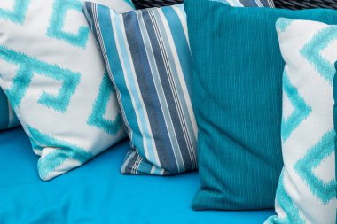 Renkli yastıklar üzerinde mavi bir kanepe. Beyaz, mavi, koyu mavi.