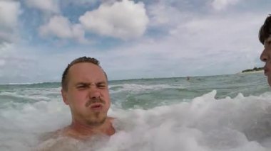 Sallayarak ve okyanusta yüzmeye mutlu çift. Balayı ocan büyük dalgalar ile eğleniyor. Tropik ada Bali, Endonezya. Ağır çekim.