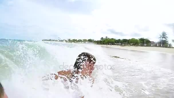 Gelukkige paar zwaaien en zwemmen In de Oceaan. Huwelijksreis met plezier in de ocan met grote golven. Tropische eiland Bali, Indonesië. Slow motion. — Stockvideo