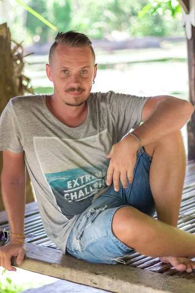 Beau homme profitant de ses vacances d'été à l'extérieur de l'île tropicale de Bali, Indonésie. Portrait de jeune homme dans un gazebo en bois . — Photo