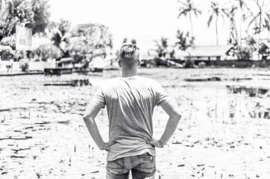 Lotus çiçek alanı gölde, tropikal Bali Adası, Endonezya poz genç adam. Siyah beyaz resim.