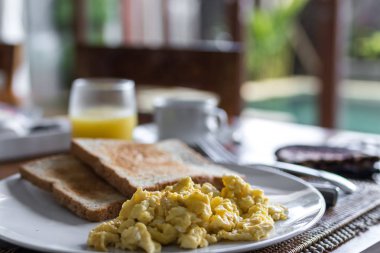 Kızarmış yumurta, beyaz tabak içinde lüks tropikal villa ile tost. Lezzetli kahvaltı kahve ve portakal suyu ile. Hafif bir arka plan üzerinde görünümü top. Bali, Endonezya.