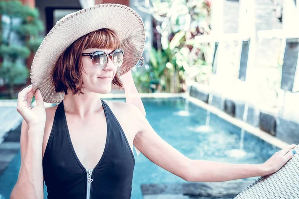 Beauté femme sexy avec chapeau et lunettes de soleil profitant de ses vacances d'été à la piscine sur une villa de luxe. Vacances d'été idyllique. Île tropicale de Bali, Indonésie . — Photo