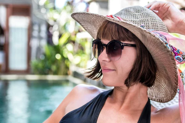 Beauty sexy woman with hat and sunglasses enjoying her summer vacation at swimming pool on a luxury villa. Summer holiday idyllic. Tropical Bali island, Indonesia. — Stock Photo, Image