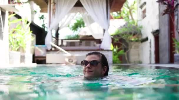 Atractiva joven mujer caucásica disfrutando del tiempo libre en su piscina en una villa de lujo, isla tropical Bali, Indonesia. Movimiento lento . — Vídeos de Stock