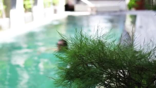 Attraktive junge kaukasische Frau, die ihre Freizeit in ihrem Swimmingpool auf einer Luxusvilla auf der tropischen Insel Bali in Indonesien genießt. Zeitlupe. — Stockvideo