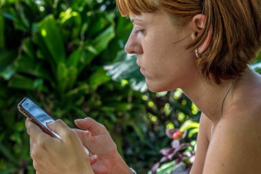 Tropikal bahçede Smartphone kullanan kadın. Tatil. Tropik ada Nusa Lembongan, Bali, Endonezya.